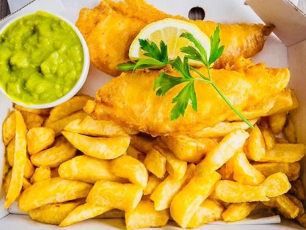 crispy fish and chips with lemon and mushy peas served at city chippy takeaway in Manchester